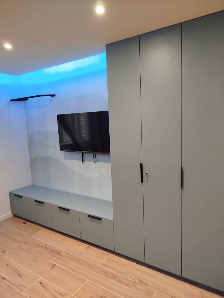 Meuble TV couleur vert eucalyptus. Quatre tiroirs en partie basse et 3 colonnes à droite