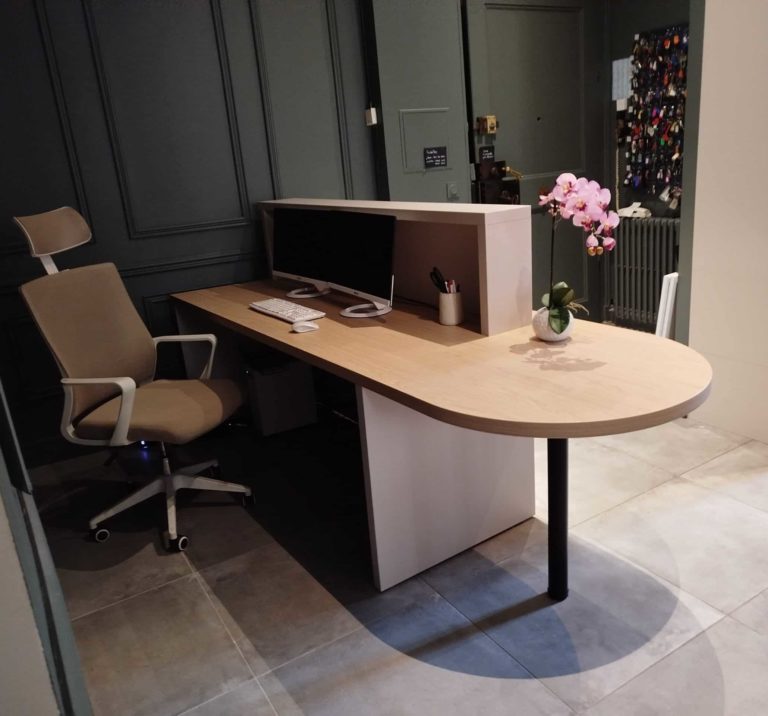 Banque d'accueil grise et bois. Grand plateau débordant pour accueillir des clients assis. Structure sur le plateau pour cacher documents et ordinateurs