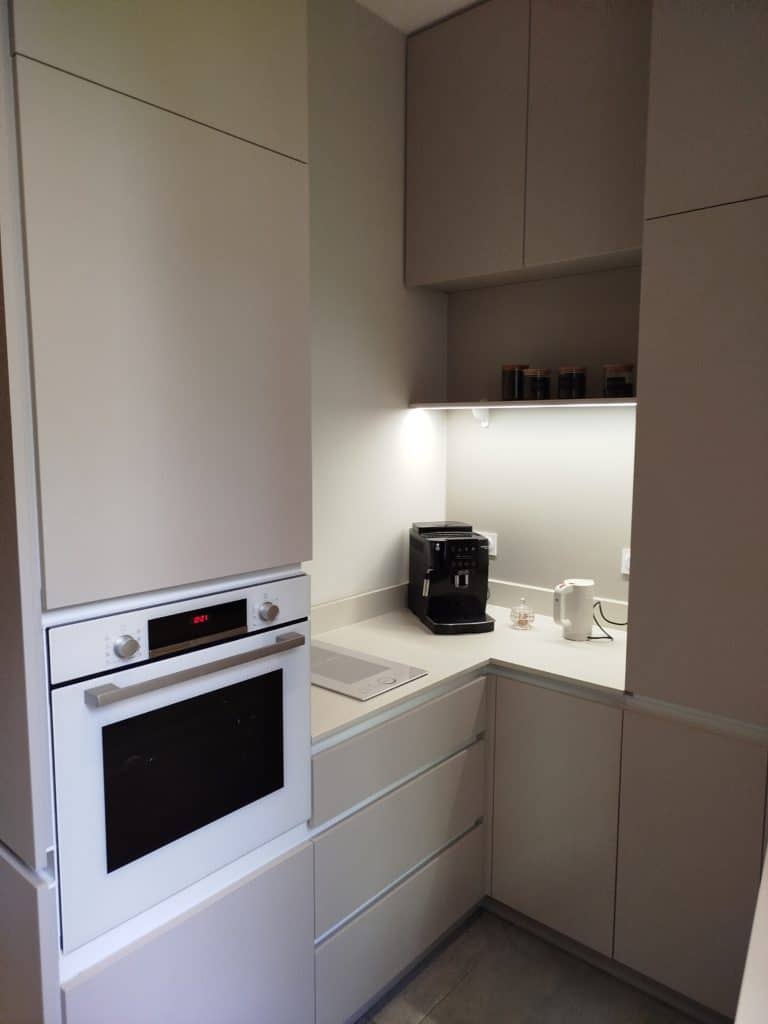 Cuisine d'angle beige grise colonne four plan pierre ruban led